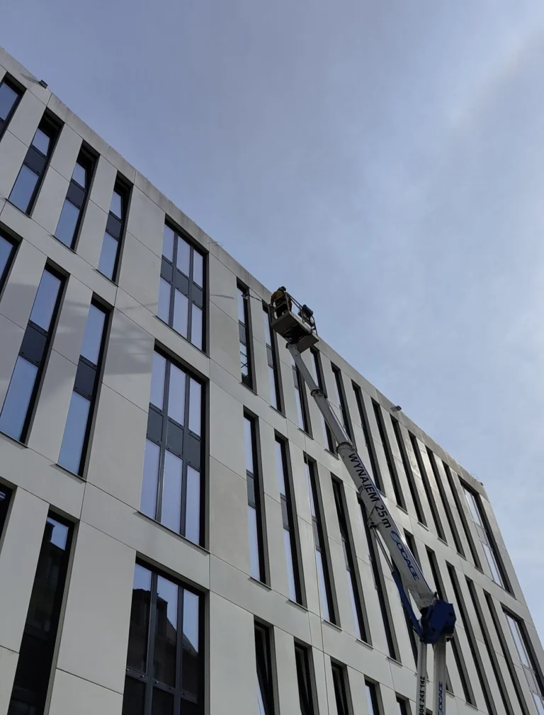 Mycie jasnej elewacji budynku komercyjnego z podnośnika