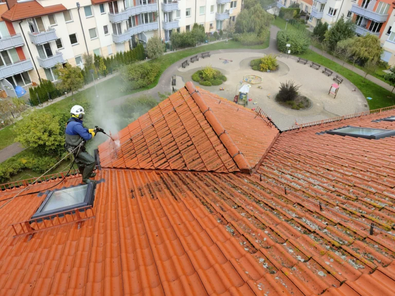 Pracownik myjący dachówkę na rozległym dachu